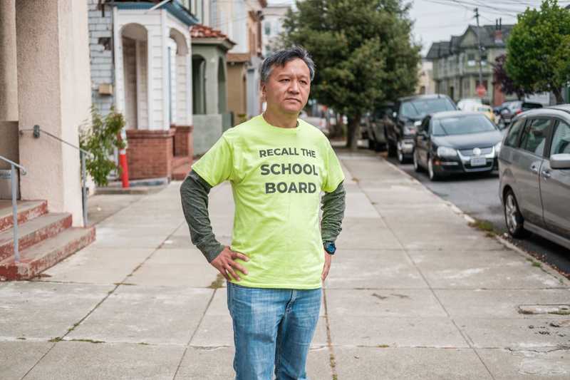 Kit Lam, an Asian American dad and school board recall supporter, stands on a sidewalk with a stern look